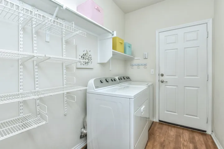 The laundry room is crisp and white, has shelves for storage.  This door leads to the garage...