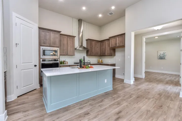 Pretty stainless vent-a-hood and white designer tile to the ceiling...Pantry door is to the left in this photo...