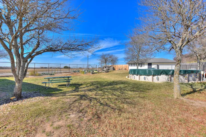 This photo shows the fenced backyard, garden area, chicken coop, workshop and the pool