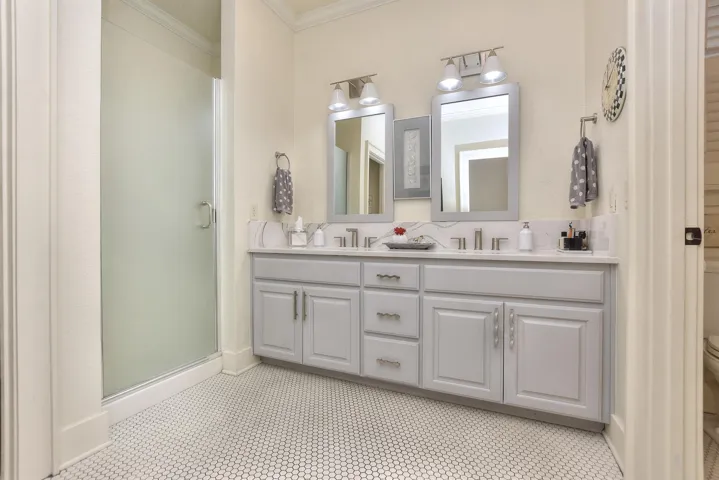 Tile floor in the primary bathroom perfectly compliments the style of the home, the gray cabinets, and the walk-in shower...The Shower has just been completely replaced..  New shower door has been ordered. On the right is the water closet...room for the commode with a great linen closet behind the door...
