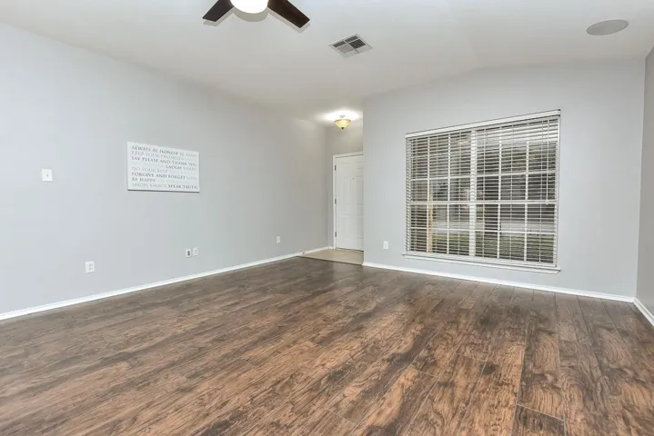 Spare room featuring dark wood-style floors, visible vents, a ceiling fan, vaulted ceiling, and baseboards