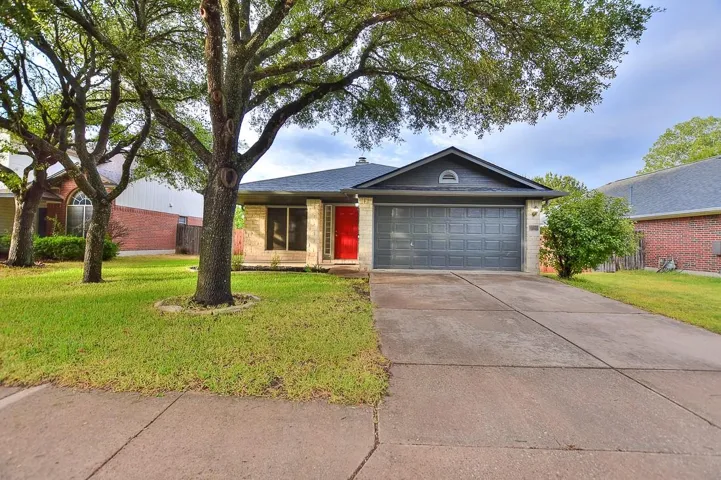 Ranch-style house with an attached garage, concrete driveway, and a front yard