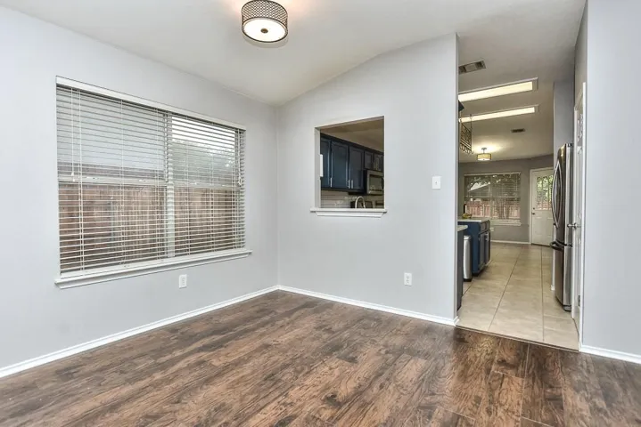 Unfurnished room featuring vaulted ceiling, light wood finished floors, visible vents, and baseboards