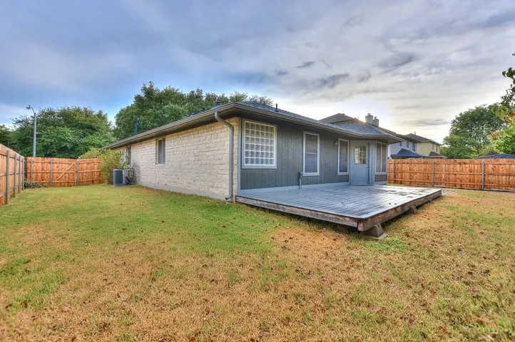Rear view of house featuring a deck, a yard, a fenced backyard, and central air condition unit