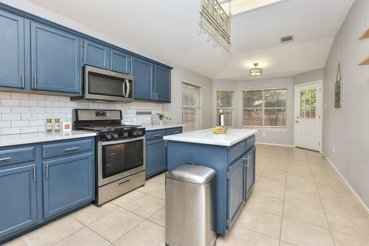 Kitchen featuring stainless steel appliances, blue cabinets, light countertops, and a center island