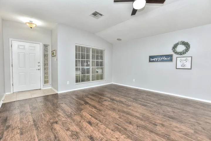 Entrance foyer with baseboards, visible vents, a ceiling fan, wood finished floors, and vaulted ceiling