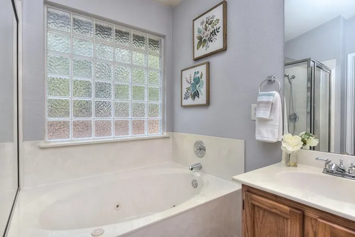 Bathroom featuring a tub with jets, a shower stall, and vanity