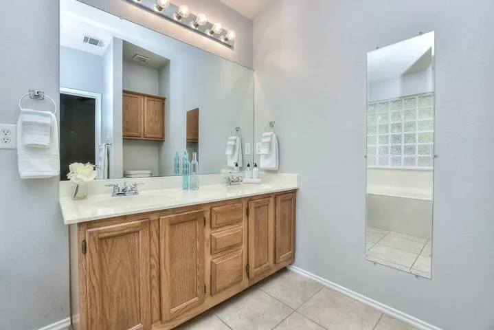 Bathroom with toilet, tile patterned flooring, a sink, and visible vents