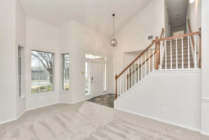 Foyer featuring living area with bay window, stairway, high vaulted ceiling 