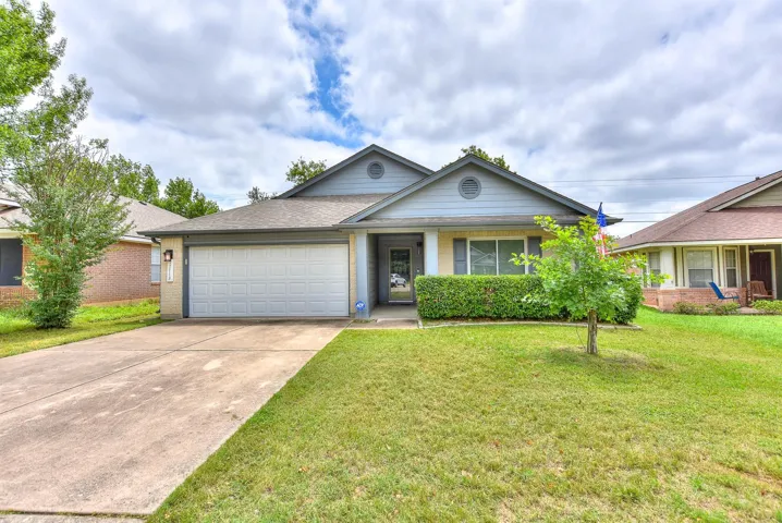 Ranch-style house featuring brick siding, an attached garage, concrete driveway, a front yard, and roof with shingles