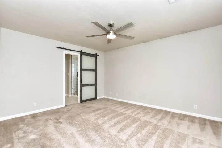 Big primary bedroom with sliding barn door leading to bath