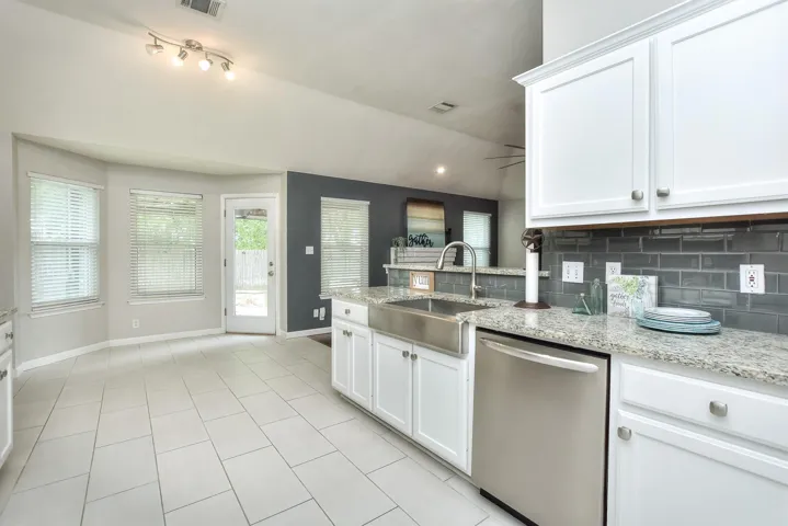 Stainless farmhouse sink, tile backsplash, granite counter tops and white cabinets.