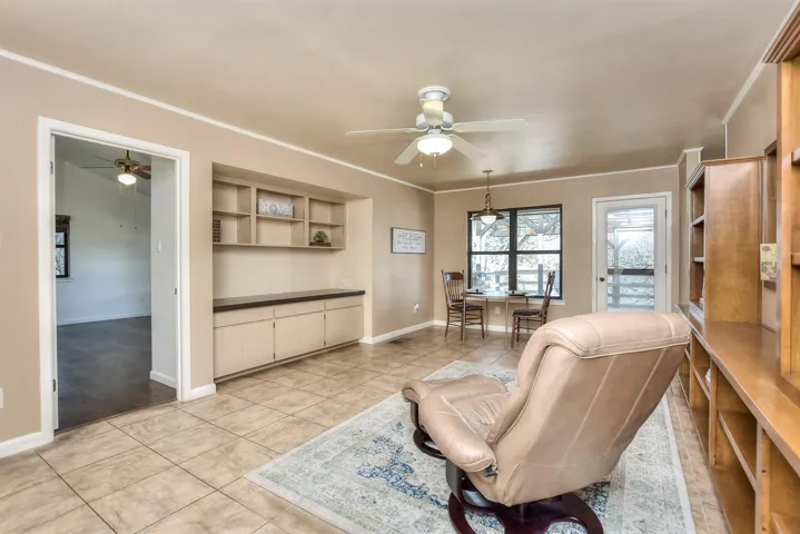 Living area featuring light tile patterned flooring, a ceiling fan, and ornamental molding
