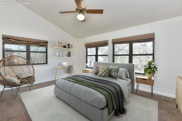 Bedroom with visible vents, baseboards, lofted ceiling, and wood finished floors