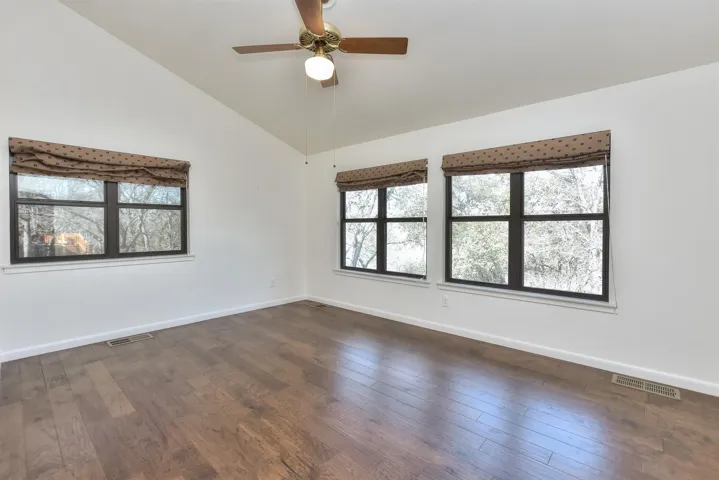 Spare room featuring visible vents, baseboards, lofted ceiling, and dark wood-style flooring