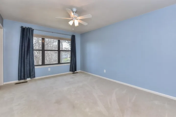 Empty room with visible vents, baseboards, light colored carpet, and ceiling fan