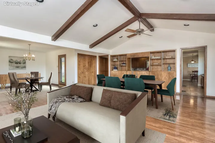 Living room featuring baseboards, high vaulted ceiling, light wood-style flooring, beamed ceiling, and ceiling fan with notable chandelier