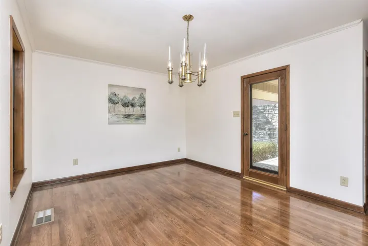 Unfurnished room featuring a chandelier, visible vents, wood finished floors, and ornamental molding