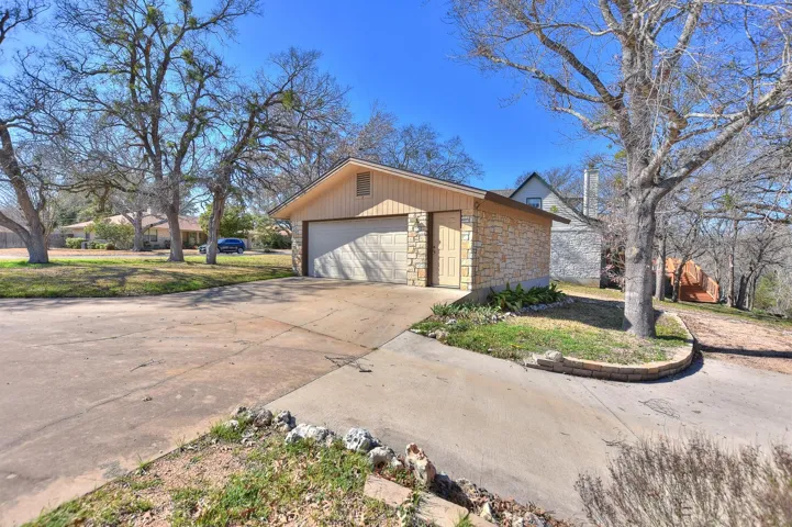 View of front of home featuring a garage, stone siding, an outbuilding, and concrete driveway