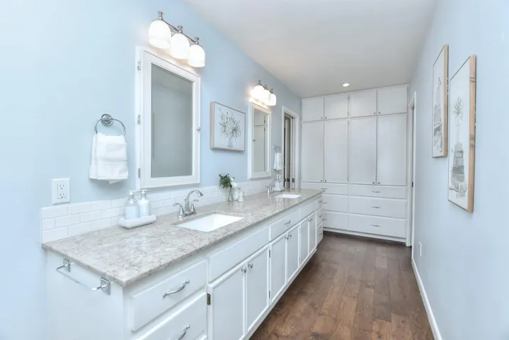 Bathroom with double vanity, wood finished floors, baseboards, and a sink