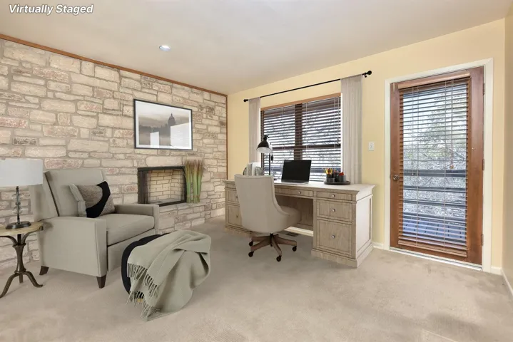 Office area featuring a fireplace, baseboards, and light carpet