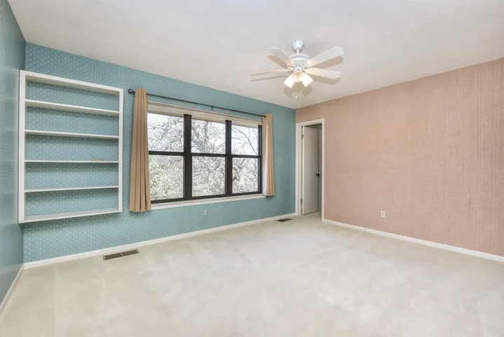 Unfurnished bedroom with wallpapered walls, carpet, and visible vents