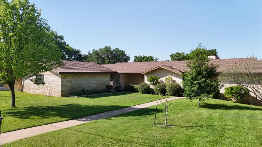 Ranch-style house with a front yard, a tile roof, and stone siding