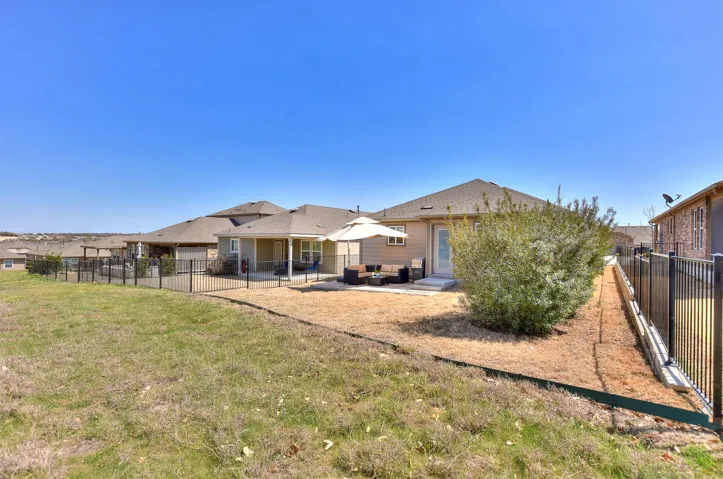 Rear view of house featuring a patio area, a lawn, fence, and an outdoor living space