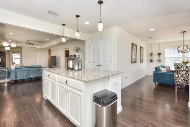 Kitchen featuring visible vents, a center island, open floor plan, ceiling fan with notable chandelier, and dark wood-style flooring
