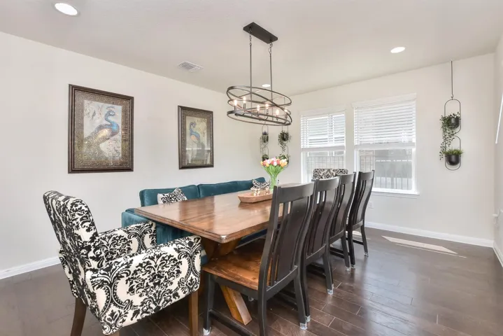 Dining space featuring an inviting chandelier, dark wood-style floors, visible vents, and baseboards