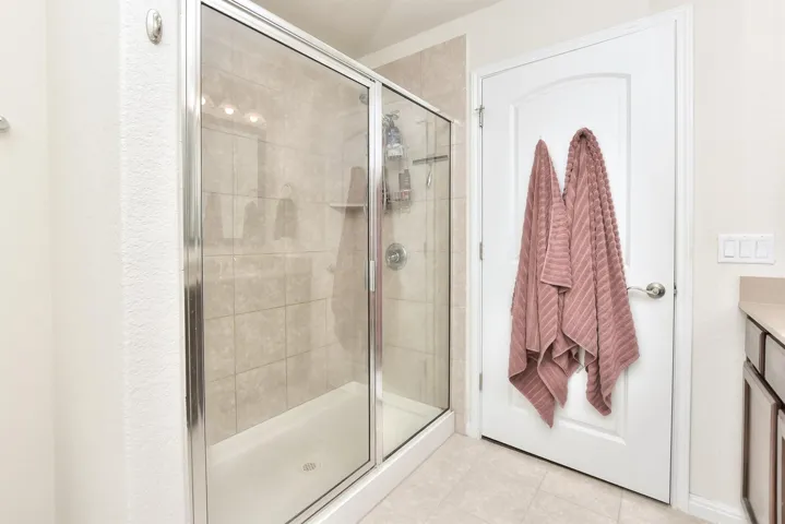Bathroom with tile patterned flooring, a shower stall, and vanity