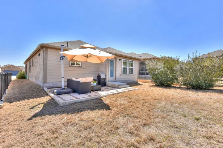 Rear view of property featuring a patio, a yard, and fence