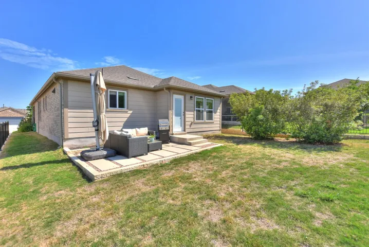 Rear view of property featuring outdoor lounge area, a patio area, a lawn, and fence