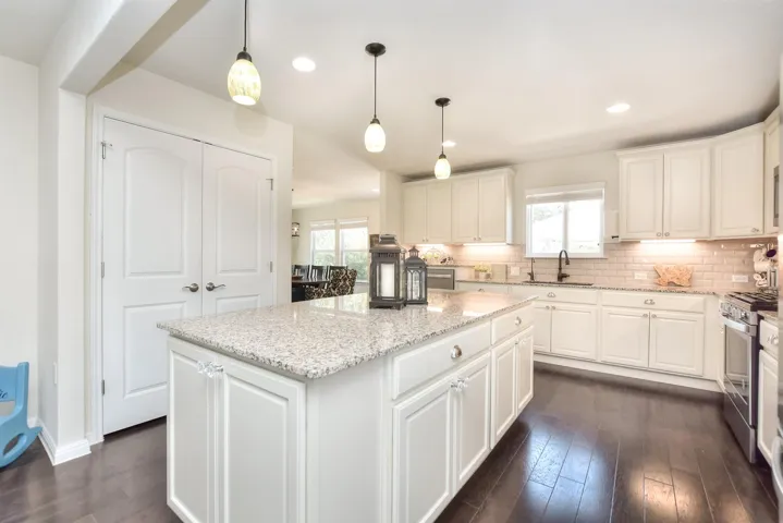 Kitchen with stainless steel gas range oven, a sink, tasteful backsplash, a center island, and white cabinets