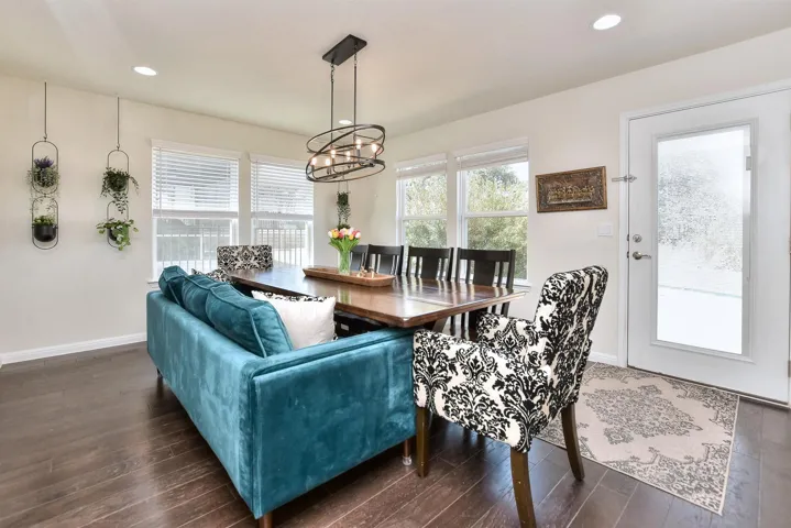 Dining area with an inviting chandelier, dark wood finished floors, and a healthy amount of sunlight