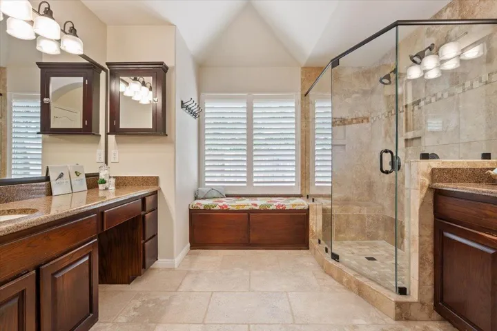 Full bathroom featuring vanity, a shower stall, and lofted ceiling