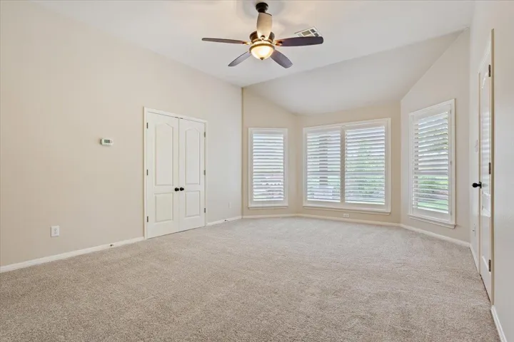 Empty room with lofted ceiling, carpet floors, and ceiling fan