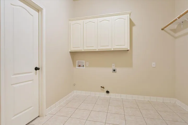 Washroom featuring hookup for a gas dryer, electric dryer hookup, hookup for a washing machine, light tile patterned floors, and cabinet space