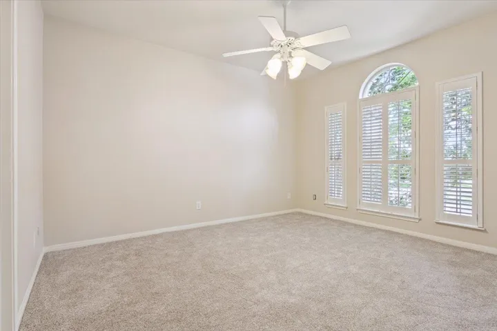 Carpeted empty room featuring baseboards and ceiling fan