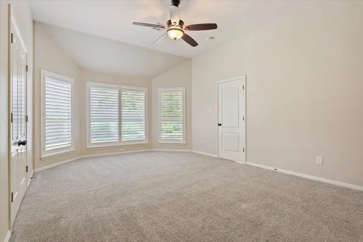 Spare room featuring lofted ceiling, a ceiling fan, and carpet floors
