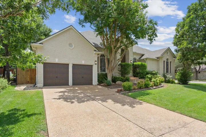 View of front of property featuring driveway, a garage, brick siding, and roof with shingles