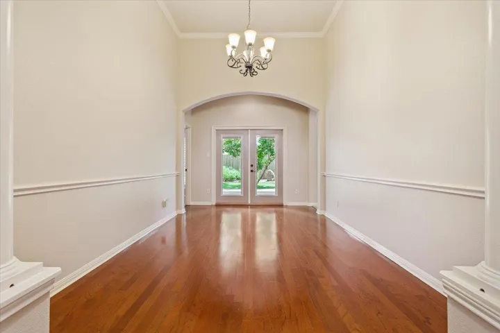 Entryway featuring arched walkways, french doors, a chandelier, wood finished floors, and ornamental molding