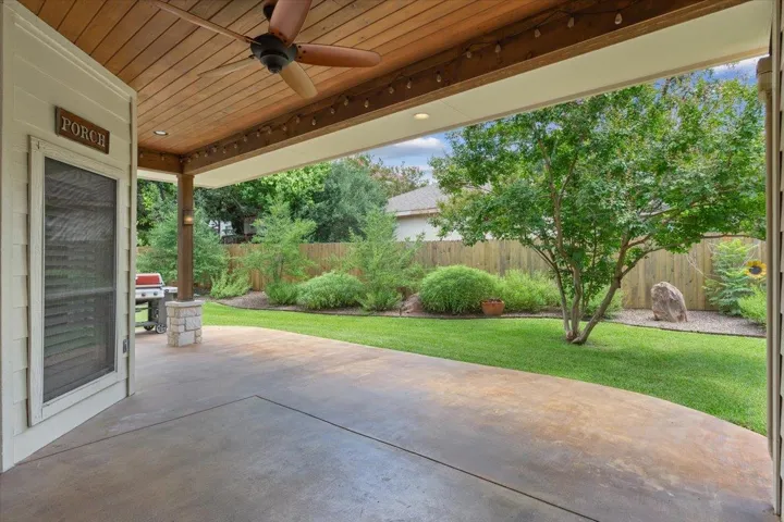 Fenced backyard featuring ceiling fan, a patio, and grilling area