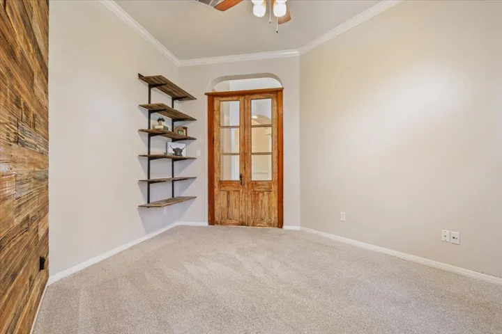Carpeted empty room with ornamental molding and a ceiling fan