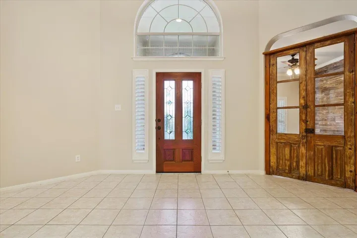 Entryway featuring ceiling fan, light tile patterned flooring, and a high ceiling