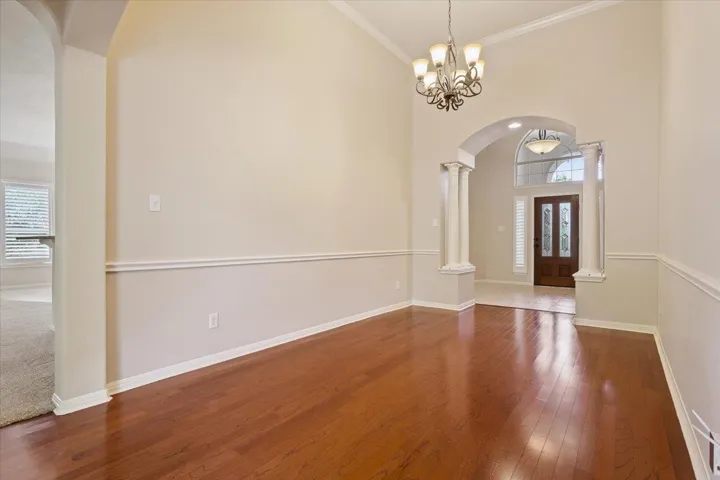 Foyer featuring healthy amount of natural light, decorative columns, arched walkways, hardwood / wood-style floors, and a high ceiling