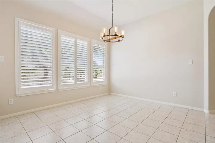Spare room featuring a chandelier, light tile patterned floors, and arched walkways
