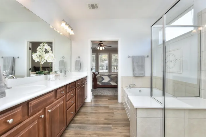 Bathroom featuring visible vents, ceiling fan, a sink, and double vanity