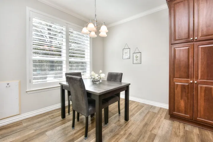 Dining area with light wood finished floors, baseboards, ornamental molding, and an inviting chandelier
