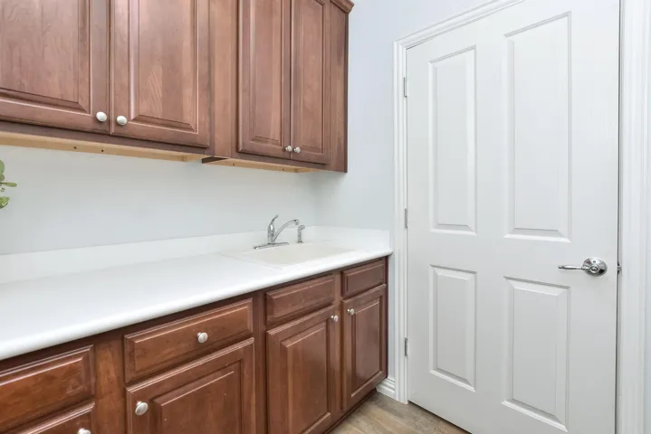 Kitchen with light countertops, a sink, and brown cabinetry